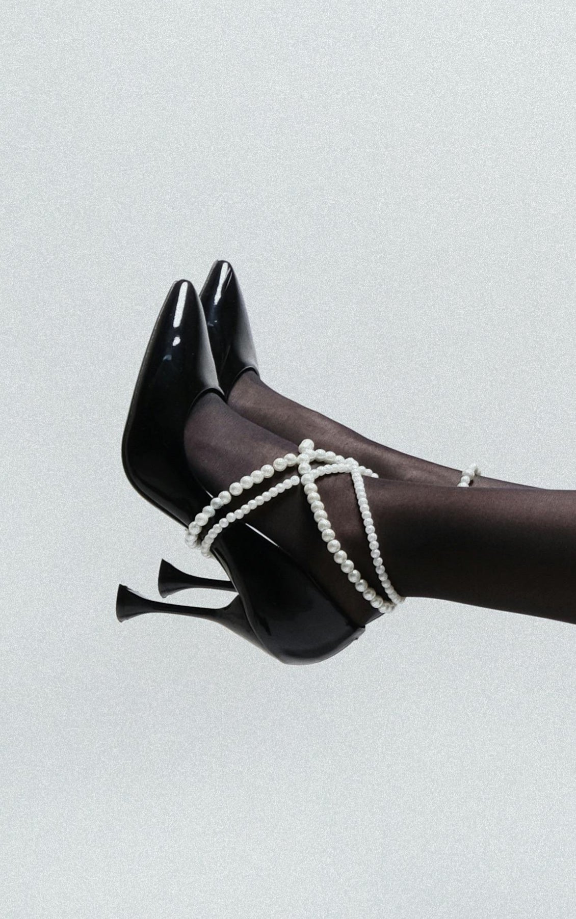 Black designer heels with pearl straps styled with sheer black tights