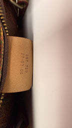Close-up of a leather tag with embossed text on a Etro Paisley leather bag.