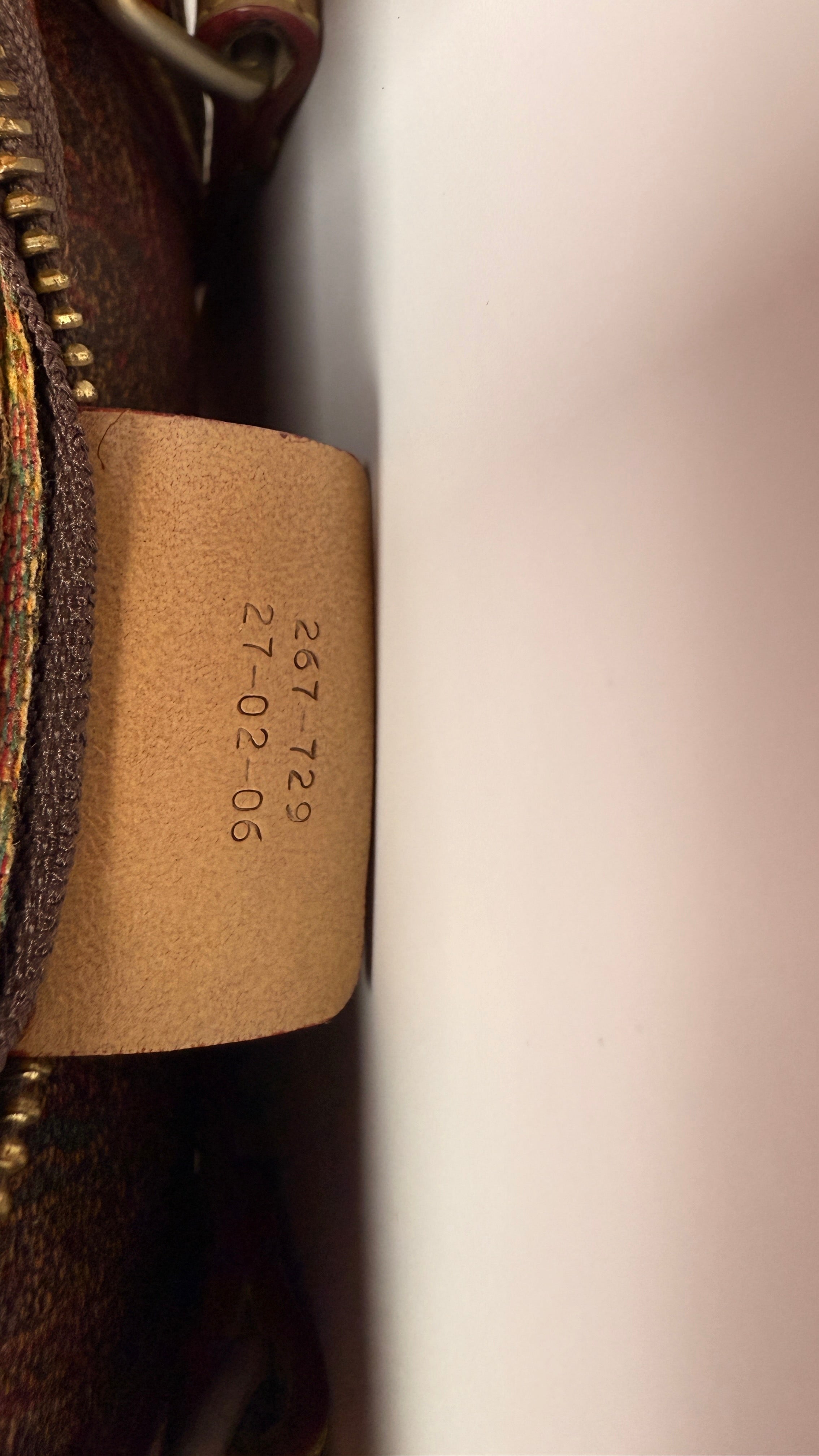 Close-up of a leather tag with embossed text on a Etro Paisley leather bag.